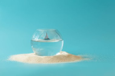 Mavi arka planda yelkenli olan akvaryum. Yaratıcı yaz tatili konsepti