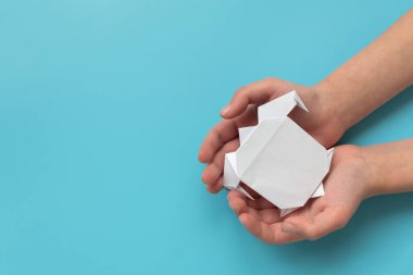 Mavi arka planda beyaz kaplumbağa tutan çocuk elleri