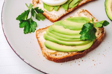 Avokadolu tost ve beyaz tabakta yumurta. Üst Manzara. Sağlıklı kahvaltı.