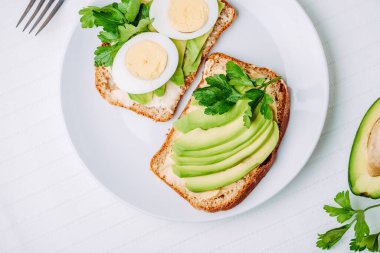 Avokadolu tost ve beyaz tabakta yumurta. Üst Manzara. Sağlıklı kahvaltı.