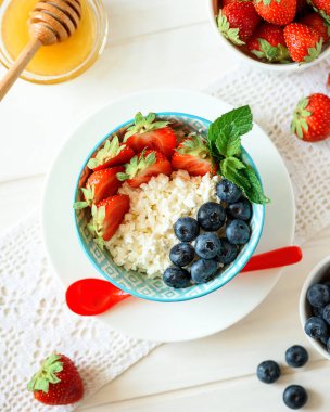 Bir kase süzme peynir, yabanmersini, çilek ve bal. Yumuşak odak