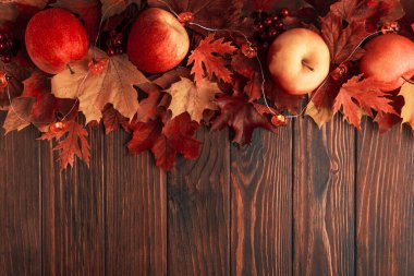 Autumn Arrangement with Apples, Leaves, Berries, and Decorative Pumpkin Lights on Wooden Surface