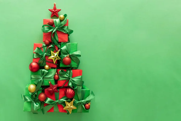 Christmas Tree Made of Gift Boxes with Ornaments on Green Background