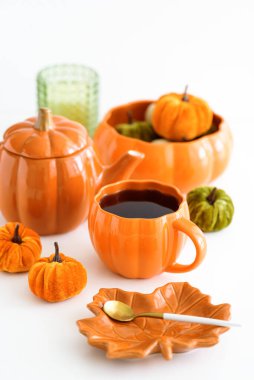 Balkabağı süslemeli sonbahar çay seti ve beyaz bir masada pasta..