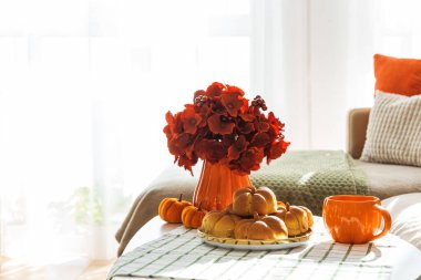 Kanepeli, yastıklı ve kahve masasında balkabaklı tarçınlı çöreklerle sonbahar oturma odası. 