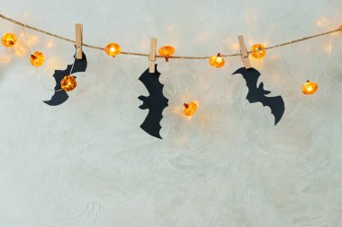 Halloween Garland with Pumpkin Lights and Bat Cutouts on Textured Wall