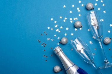 Champagne Bottle and Flutes with Silver Ornaments for New Year Celebration on Blue Background