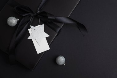 Siyah Noel Hediye Kutusu, Saten Kurdele ve Beyaz Boş Etiket ile Karanlık Tatil Arkaplanı
