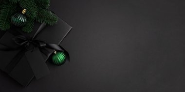 Siyah Noel Hediye Kutusu, Saten Kurdele ve Yeşil Süsler ile Karanlık Tatil Arkaplanı