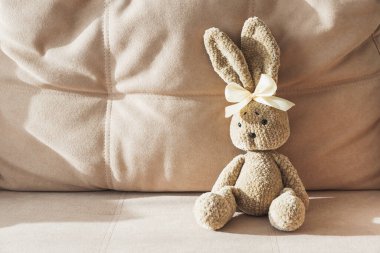Plush Crochated Bunny ve sarı kurdeleli Bej koltukta oturuyor