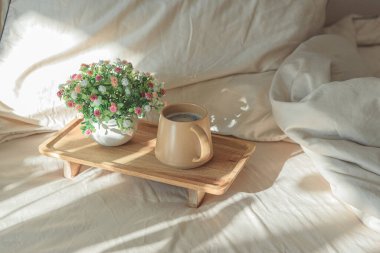 Kahve fincanı ve tahta tepside saksı bitkisiyle yatakta kahvaltı