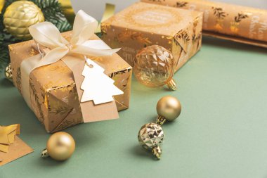 Yeşil Arkaplanda Süsler ve Etiketlerle Noel Hediyesi Paketleme Flatlay