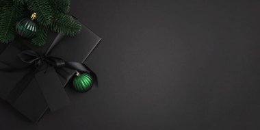 Siyah Noel Hediye Kutusu, Saten Kurdele ve Yeşil Süsler ile Karanlık Tatil Arkaplanı