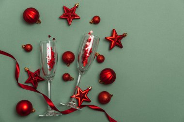 Şampanya flütleri ve Yeşil Arkaplanda Kırmızı Noel süsleri. Mutlu yıllar ya da Noel kutlamaları