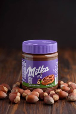 Lviv, Ukrayna - 19 Haziran 2025: Ahşap arka planda fındıklı Milka Fındık Ezmesi kavanozu. Ön görünüm