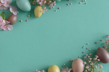 Pastel Paskalya Yumurtaları ve Çiçekleri Teal Arkaplanda. Neşeli Bahar Flatlay