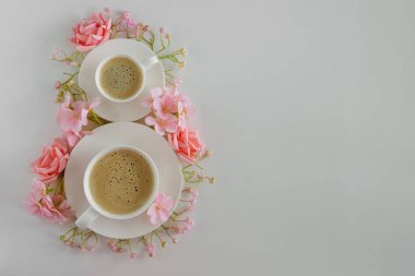 Kahve fincanları ve sekiz şeklinde pembe çiçekler. Uluslararası Kadınlar Günü için Zarif Flatlay