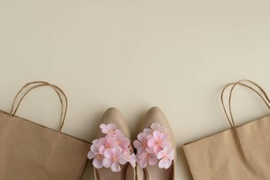 Bej arka planda Eko Poşetler ve Çiçekli Yüksek Topuklar. Bayramlık Bahar Moda Düzlüğü