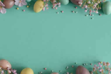 Pastel Paskalya Yumurtaları ve Çiçekleri Teal Arkaplanda. Neşeli Bahar Flatlay