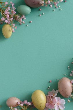 Pastel Paskalya Yumurtaları ve Çiçekleri Teal Arkaplanda. Neşeli Bahar Flatlay