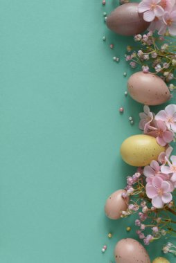 Pastel Paskalya Yumurtaları ve Çiçekleri Teal Arkaplanda. Neşeli Bahar Flatlay