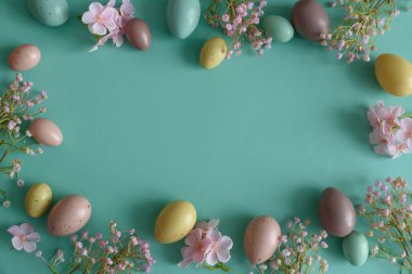 Pastel Paskalya Yumurtaları ve Çiçekleri Teal Arkaplanda. Neşeli Bahar Flatlay