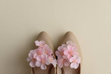 Krema arka planında pembe çiçekli bej yüksek topuklar. Bayramlık Bahar Moda Düzlüğü