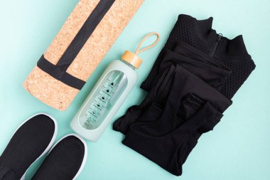 Spor kıyafetleri ve aksesuarlar mavi arka planda serili..