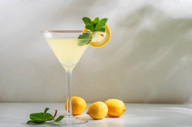 Taze limon dilimleri ve beyaz arka planda naneli şekerlerle süslenmiş parlak ve ferahlatıcı limoncello spritz kokteyli.