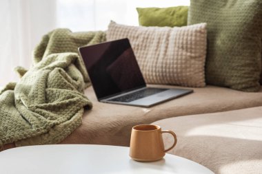 Laptop koltukta, kahve fincanı masada. Sıcak Bahar Ev Çalışma Alanı