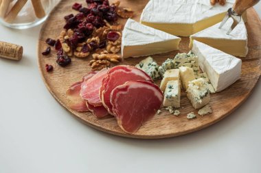 Çeşitli peynirler, kurutulmuş etler, cevizler, kuru kızılcıklar, ekmek çubukları, zeytin ve kırmızı jöle içeren zarif şarküteri kompozisyonu, iki kadeh kırmızı şarapla eşleştirildi.