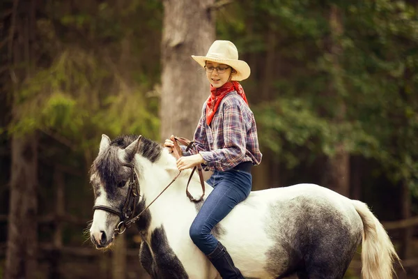 小女孩骑着马在森林里 马术女孩 头戴帽子的女牛仔 — 图库照片
