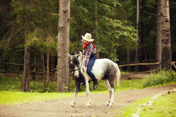 小女孩骑着马在森林里 马术女孩 头戴帽子的女牛仔 — 图库照片
