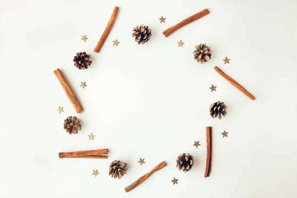 Pine corns, gold stars and cinnamon sticks on white background