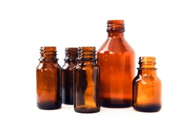 Beyaz arka planda koyu kahverengi şişeler. Küçük boş şişeler.