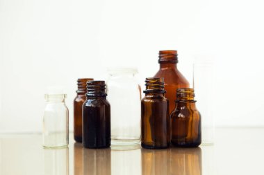 Beyaz arka planda koyu kahverengi şişeler. Küçük boş şişeler