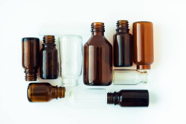 Beyaz arka planda koyu kahverengi şişeler. Küçük boş şişeler