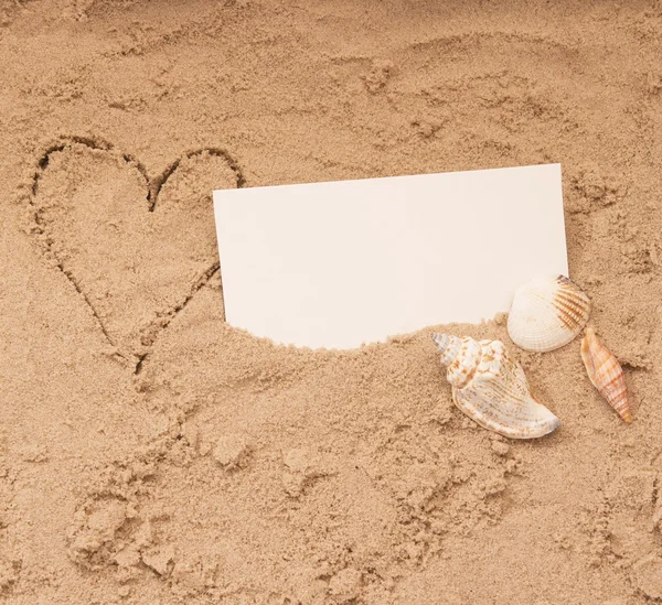 Copyspace prázdný papír na plážový písek, srdce a mušle — Stock fotografie