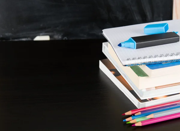 Livros escolares e marcador contra quadro negro — Fotografia de Stock