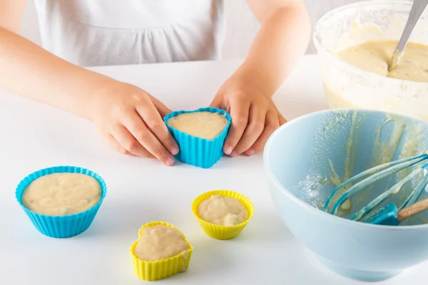 Ребенок кладет тесто в банки для кексов — стоковое фото