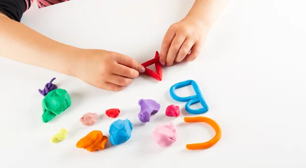 Manos de niño con arcilla colorida. Cartas de molde — Foto de Stock