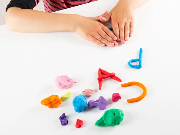 Barnet händer med färgglada lera. Mögel bokstäver — Stockfoto