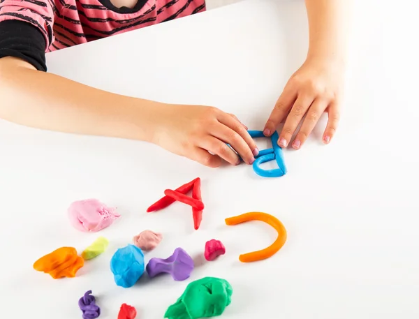 Mãos de criança com barro colorido. Cartas moldadas — Fotografia de Stock