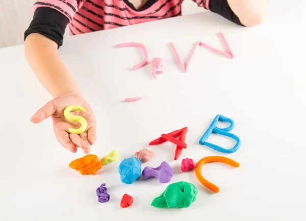 Manos de niño con arcilla colorida. Cartas de molde — Foto de Stock