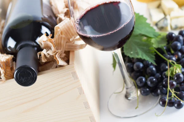 Copo de vinho tinto e uva, queijo e garrafa de vinho em branco — Fotografia de Stock