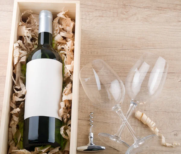 Bottle of white wine in wooden box and empty wine glasses