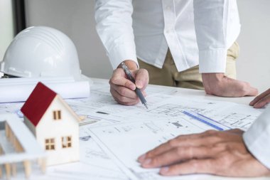 İnşaat mühendisliği ya da mimar bir proje planı ve inşa modelini tartışırken, aynı zamanda şantiyedeki mimari proje için yapılan çizim toplantısının bilgilerini kontrol ediyor..