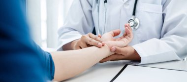 Doktor nabız atışını kontrol etmek için hastayı bileğinden tuttu. Klinikte çalışan doktor tedaviyi, sağlık hizmetini ve hastaya reçeteli ilaç yazmayı açıkladı.