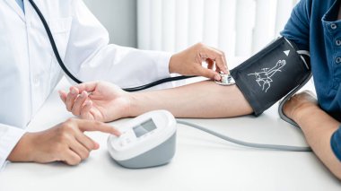 Doktor kan basıncını kontrol ediyor ve aynı zamanda steteskop kullanıyor, hastanın hastalığının nedenini kontrol etmek ve hastane bürosundaki sağlık hizmetlerine danışmak için.