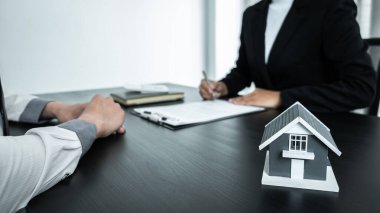 Emlak komisyoncusu müşteri kararına sunum yapıyor. Onaylanmış mortgage başvurusu, ipotek kredisi teklifi ve ev sigortası ile sözleşme imzalama emlak sözleşmesi imzalıyor..